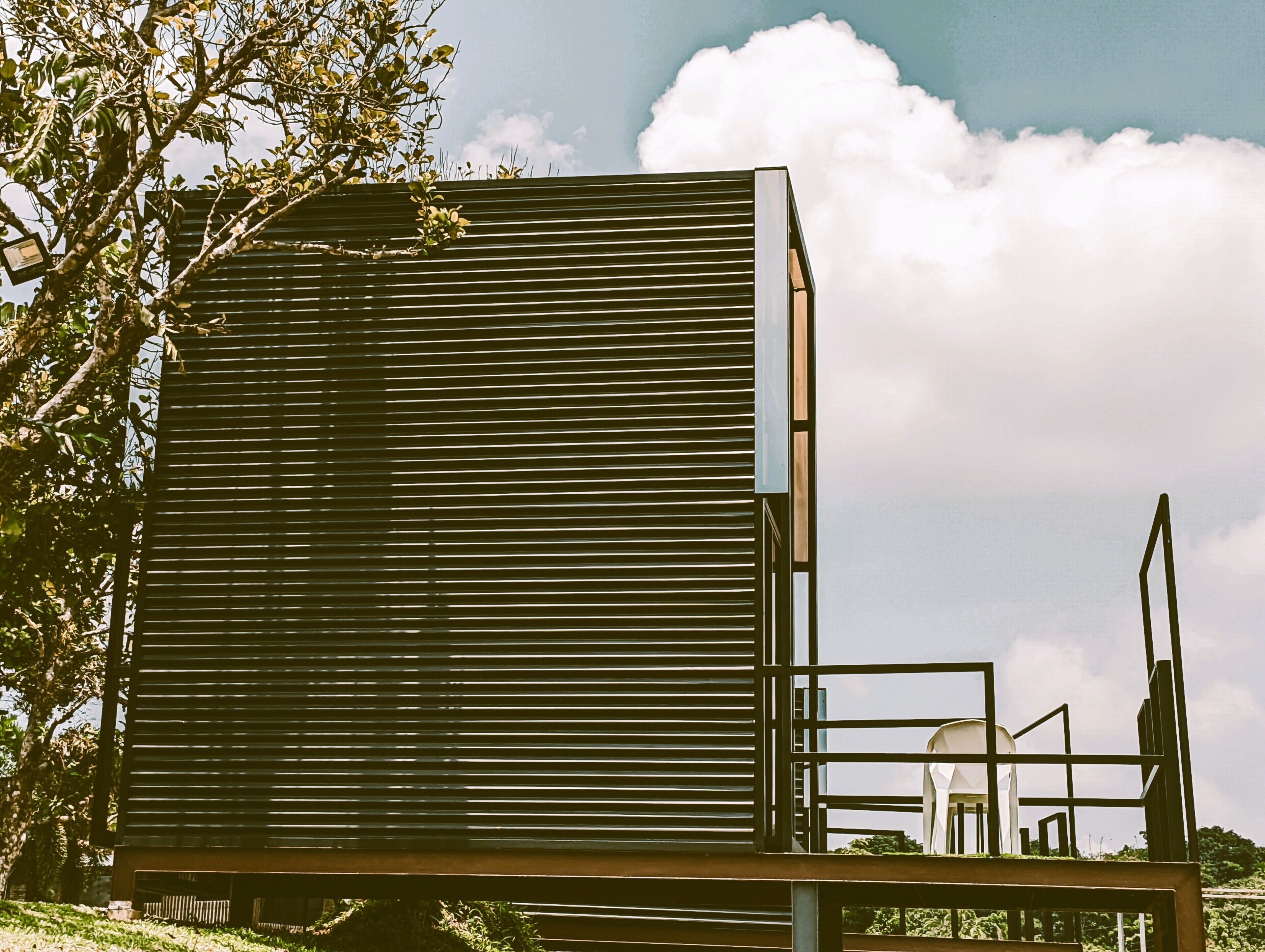 A modern building with horizontal slats, a metal frame structure, and a view of the sky.