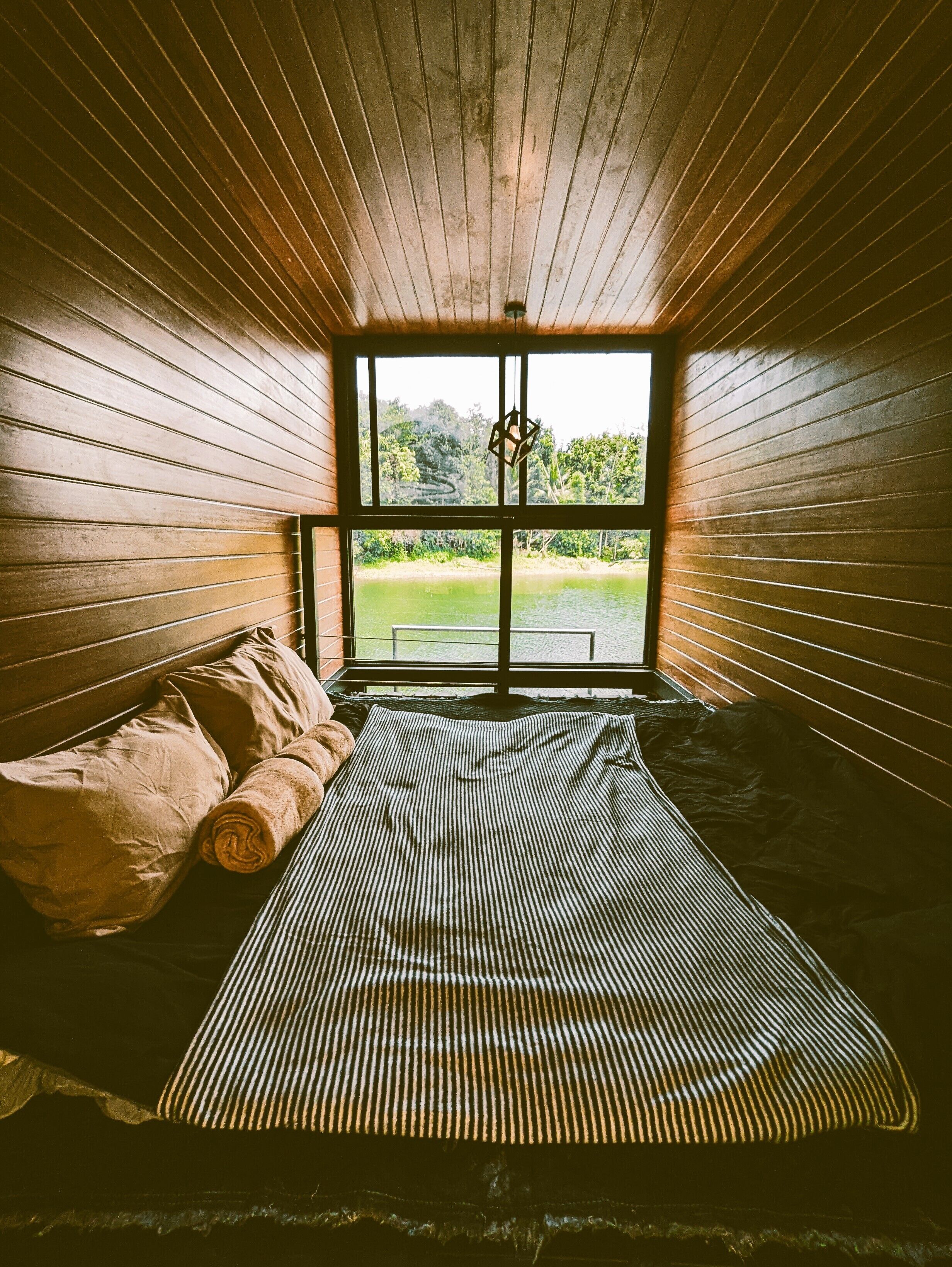 Una stanza con un letto, una finestra e vista su del verde all'esterno.