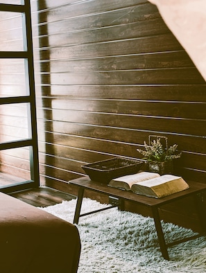 Een gezellig hoekje om te lezen, met een houten bank, een mand en een boek op een vloerkleed.