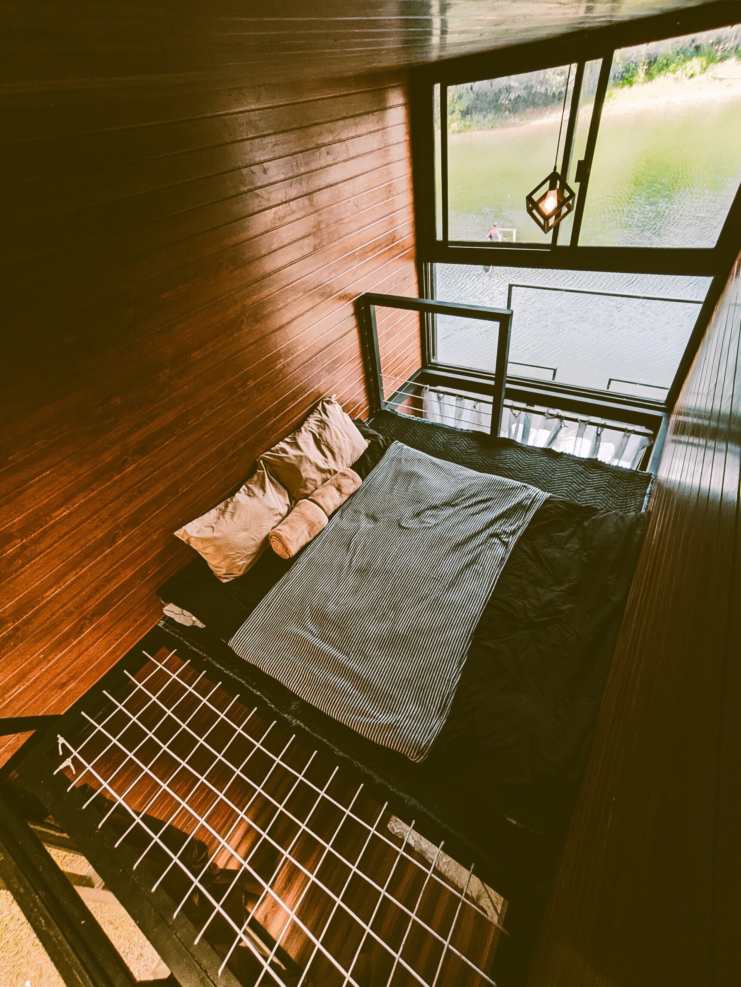 Ein Zimmer mit Bett, Fenster und Blick auf ein Gewässer.