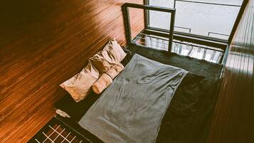 Ein Zimmer mit Bett, Fenster und Blick auf ein Gewässer.