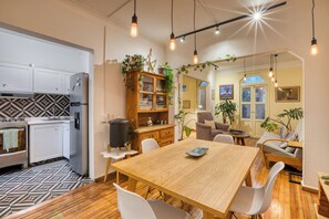 Eine moderne Küche mit weißen Schränken, einer schwarz-weißen Spritzschutzwand und einem Holzespeisetisch mit weißen Stühlen.