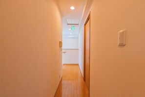 A narrow hallway with a wooden floor, beige walls, and a door on the right.