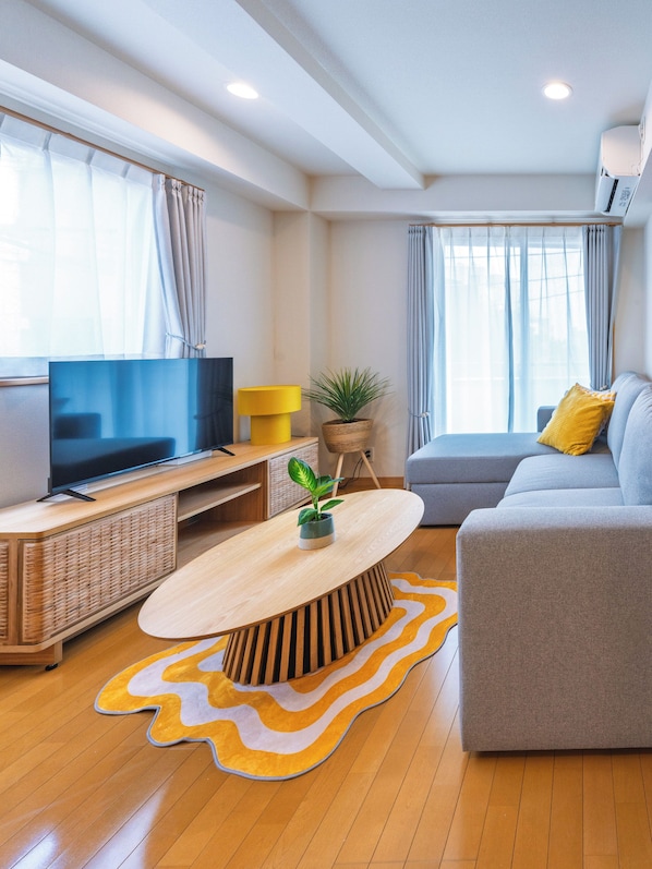 A modern living room with a flat-screen TV, a sofa, a coffee table, and a potted plant. - THE AOCA TOKYO JIYUGAOKA (Setagaya-ku)