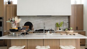 A modern kitchen with a central island, wooden cabinets, a marble countertop, and a built-in stove. - Casa Landing where your soul gets refreshed! A Lakeview custom build with a pool (Carlton Landing)