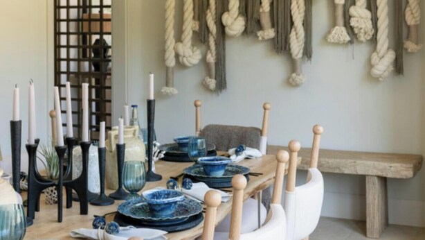 A dining area with a wooden table set for four, featuring blue and white dinnerware, black candle holders, and white chairs. - Casa Landing where your soul gets refreshed! A Lakeview custom build with a pool (Carlton Landing)