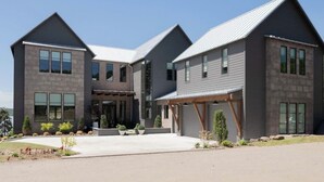 A modern two-story house with a covered driveway, large windows, and a well-maintained garden. - Casa Landing where your soul gets refreshed! A Lakeview custom build with a pool (Carlton Landing)