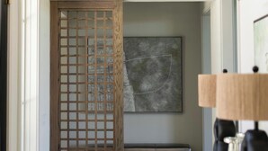 A modern interior with a wooden screen door, a large abstract painting, and a contemporary light fixture. - Casa Landing where your soul gets refreshed! A Lakeview custom build with a pool (Carlton Landing)