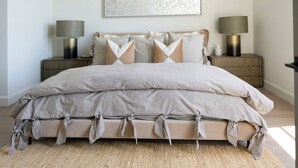 A bed with striped bedding, two bedside lamps, and a large abstract painting on the wall. - Casa Landing where your soul gets refreshed! A Lakeview custom build with a pool (Carlton Landing)