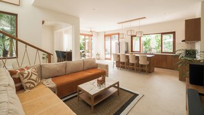 A spacious living area with a sofa, coffee table, and dining area with chairs. - Villa Lurline (Kuta Selatan)