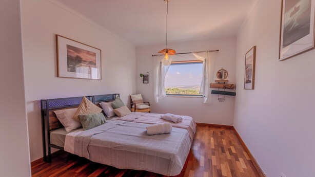 Una camera da letto con un letto, una sedia, una finestra vista e una lampada a sospensione.