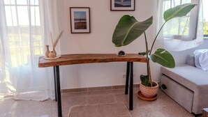 Un tavolo in legno con gambe nere, una pianta in vaso e due quadri appesi al muro.