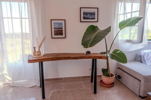 A wooden table with black legs, a potted plant, and two framed pictures on the wall. - Detached Beach House near Santa Cruz | Surf, Yoga & Ocean Views | Sleeps 8–10⁠ (Silveira)