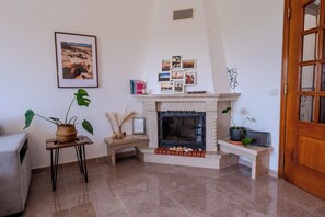 Ein Wohnzimmer mit Kamin, einem gerahmten Foto an der Wand und einem Blumentopf.