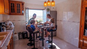 Una famiglia a tavola nella cucina, con sgabelli, un frigorifero e una finestra vista.