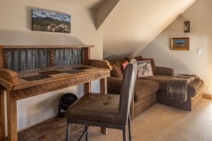 A cozy loft bedroom with a wooden bench, a cushioned chair, a brown sofa, and a small table. - New Listing! Slopeside at Cowboy Heaven (Big Sky)