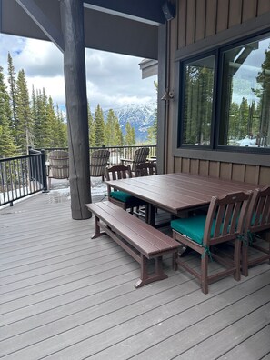 A covered outdoor deck with a wooden table and chairs, a bench, and a view of snow-capped mountains. - New Listing! Slopeside at Cowboy Heaven (Big Sky)