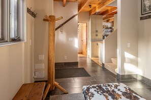 A hallway with a wooden coat rack, a bench, and a fur rug. - New Listing! Slopeside at Cowboy Heaven (Big Sky)