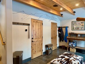 A room with wooden doors, a coat rack, a small stool, a cowhide ottoman, and a map on the wall. - New Listing! Slopeside at Cowboy Heaven (Big Sky)