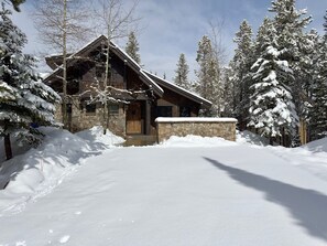 A snow-covered lodge with a stone entrance and wooden exterior. - New Listing! Slopeside at Cowboy Heaven (Big Sky)