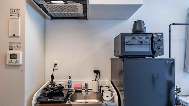 A compact kitchen with a microwave, a refrigerator, a sink, and a small countertop.