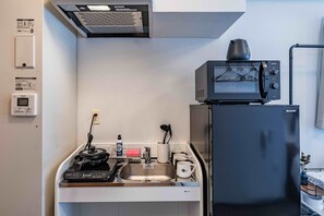 Cocina compacta con microondas, refrigerador, pileta y una pequeña encimera.