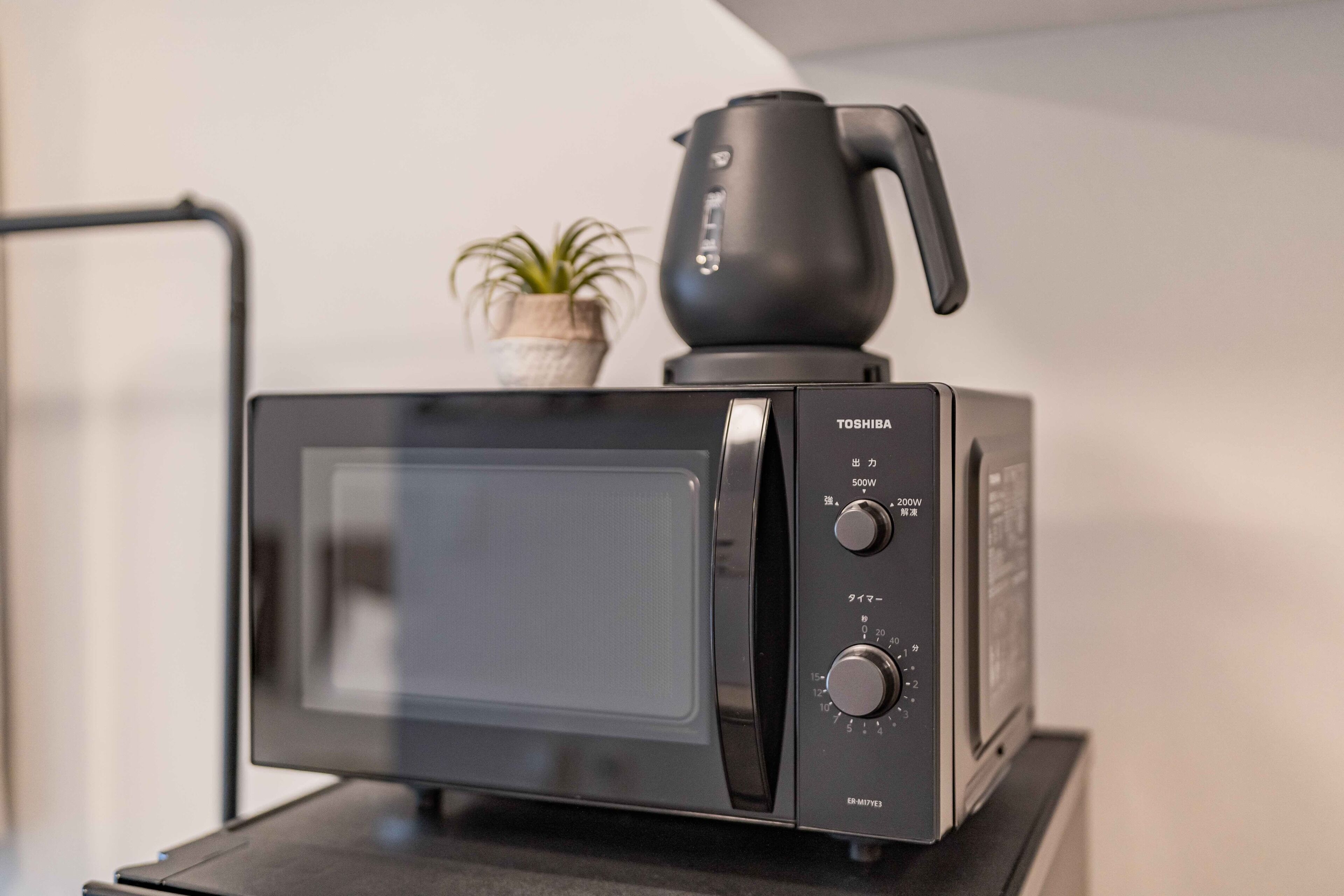 A black microwave oven with a digital display, power settings, and a water boiler on top.