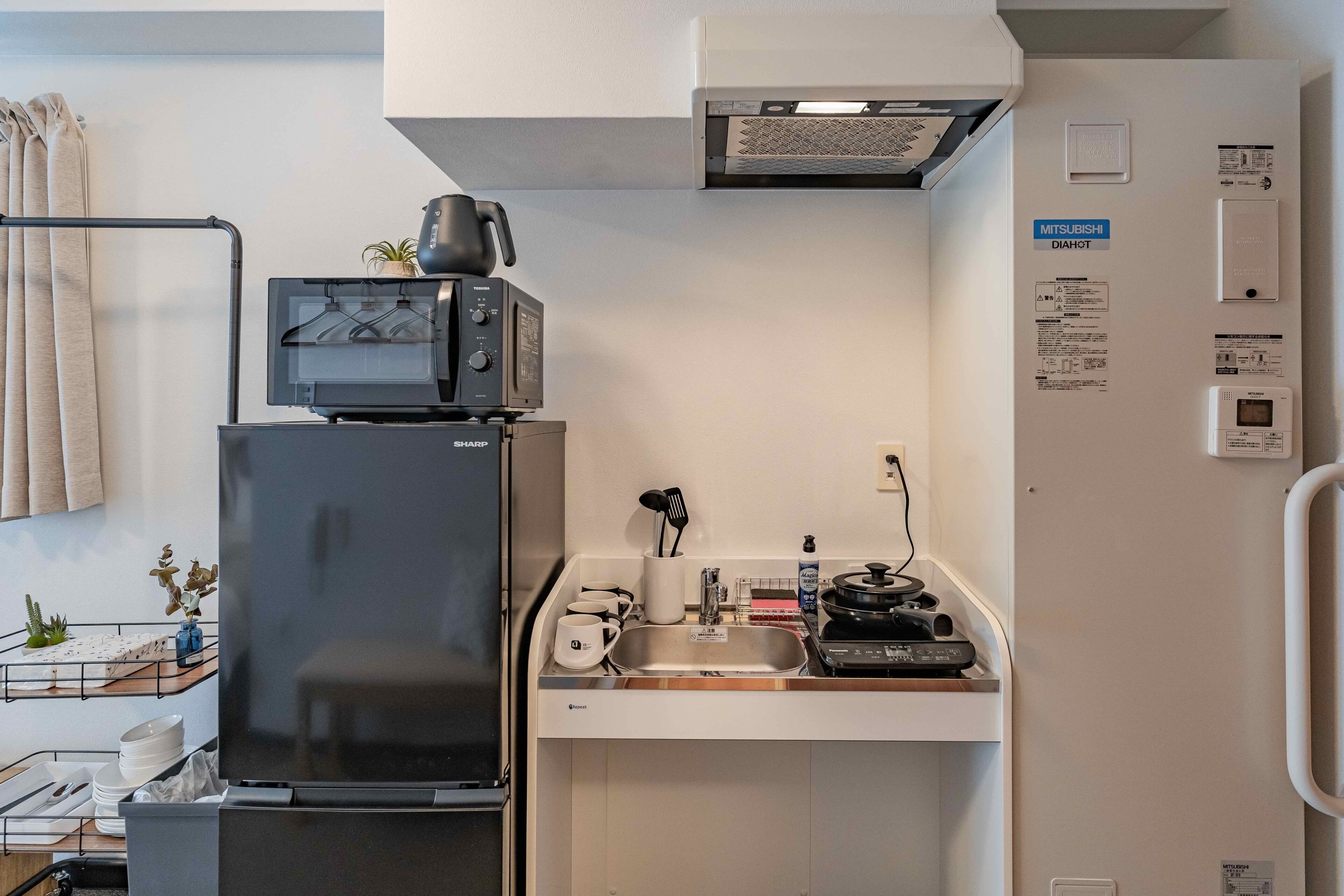A compact kitchenette with a refrigerator, microwave, and a small sink area.