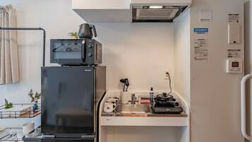 A compact kitchenette with a refrigerator, microwave, and a small sink area.