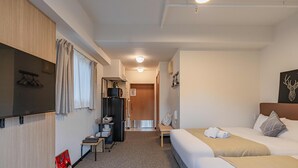 Una camera d'albergo con due letti, una scrivania, un armadio e un angolo cottura.