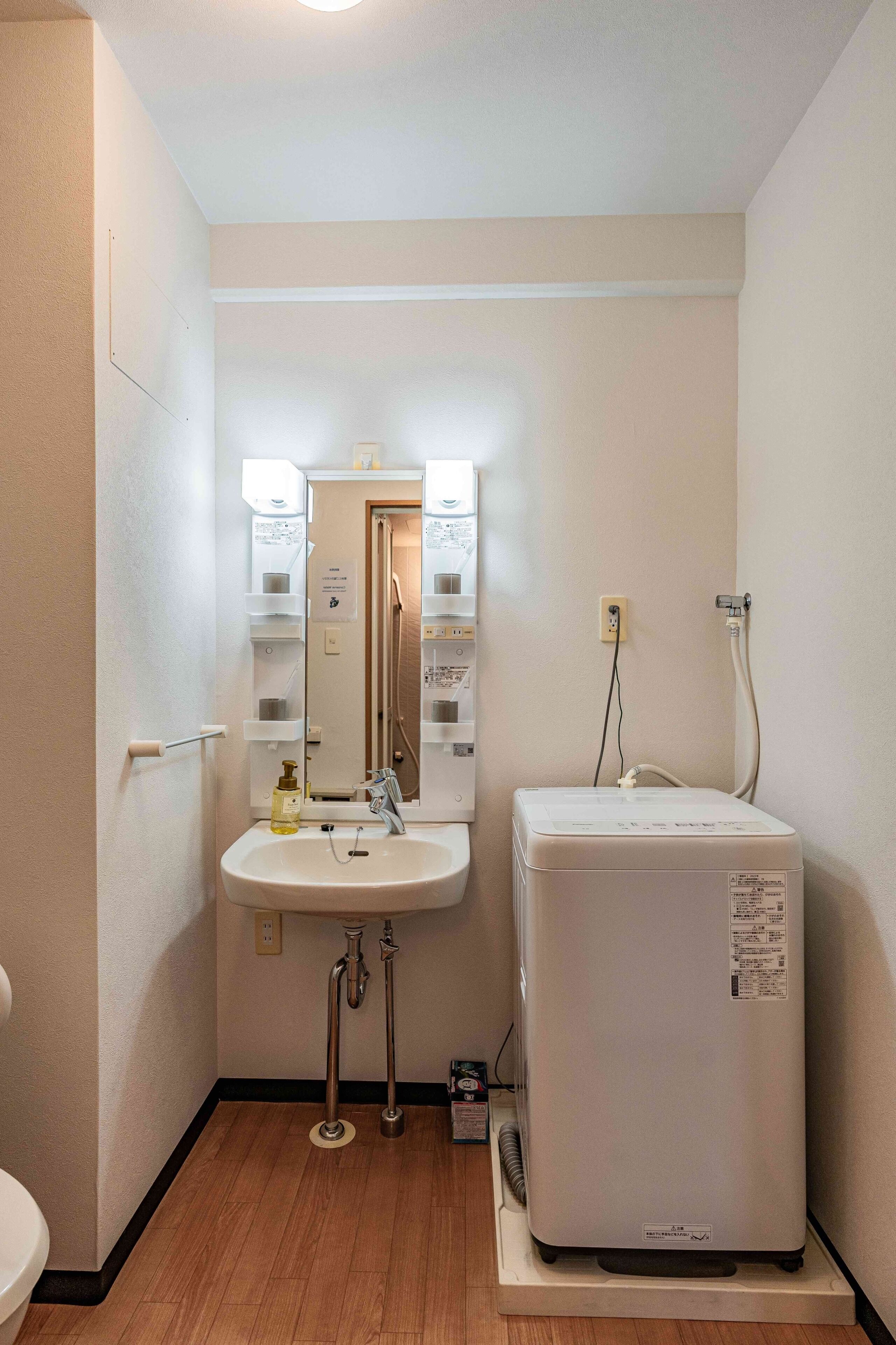 A small bathroom with a sink, mirror, and a white heater unit.
