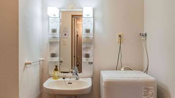 A small bathroom with a sink, mirror, and a white heater unit.