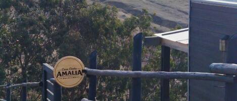 A fenced area with a sign reading 'Casa Costa AMALIA' and a view of a hilly landscape.