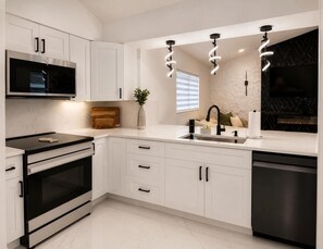 A modern kitchen with white cabinetry, a built-in microwave, a stove, and a dishwasher. - Pleasant 3-bedroom house with pool in charming Palm Harbor (Palm Harbor)