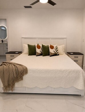 A bedroom with a bed, nightstands, a mirror, and a ceiling fan. - Pleasant 3-bedroom house with pool in charming Palm Harbor (Palm Harbor)