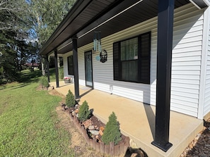 A residential house with a covered porch, a front yard with a rock garden, and a mailbox.