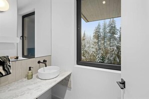 Une salle de bain moderne avec une grande fenêtre, un lavabo rond et un miroir.