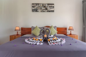 Habitació d'hotel amb un llit, dues taules de nit, un quadre a la paret i un arranjament decoratiu de tovalloles.