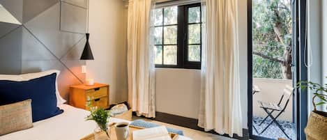 Ein modernes Schlafzimmer mit Bett, Nachttisch, Lektüre und Blick ins Freie.
