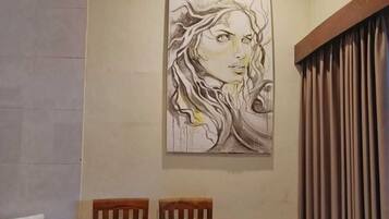 A room with a wooden chair, a drum, and a painting on the wall.