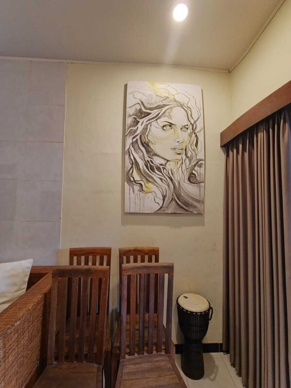 Une pièce avec une chaise en bois, un tambour et un tableau accroché au mur.