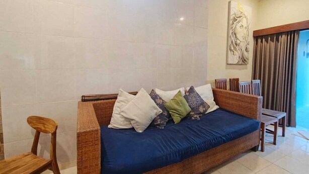 Una habitación con sofá, sillón, un cuadro y ventana.