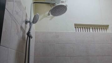 A shower area with a handheld showerhead and a wall-mounted showerhead, both with hoses.
