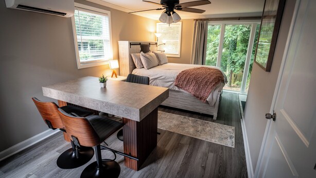 A compact bedroom with a bed, bedside table, and a window with a view of greenery. - Studio Guesthouse with AC in charming Decatur (Decatur)