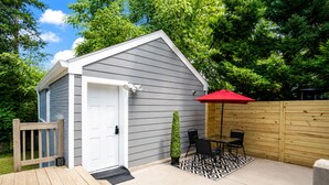 A small shed with a white door, a wooden deck, a black and white patterned rug, and a red umbrella. - Studio Guesthouse with AC in charming Decatur (Decatur)
