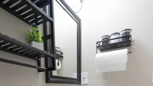 A bathroom with a white toilet, a sink with a mirror above it, and a shelf with toiletries. - Studio Guesthouse with AC in charming Decatur (Decatur)