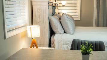 Ein Hotelzimmer mit einem Bett, einem Nachttisch, einer Lampe und einem kleinen Topfpflanzen.