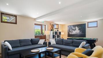 A modern living room with a sofa set, a pool table, and a painting on the wall.