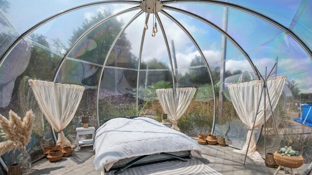 Ein Bett in einer kuppelförmigen Struktur mit Blick ins Freie.