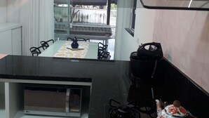 Een keuken met een zwart aanrecht, een fornuis, een waterkoker en een eethoek met een tafel en stoelen.